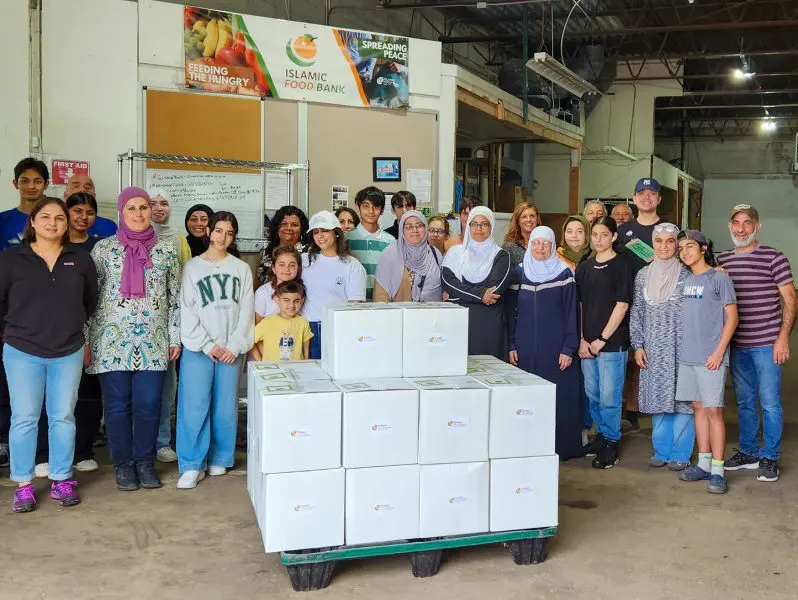 Group of volunteers gather around packed white boxes after Eid al-Adha packing event